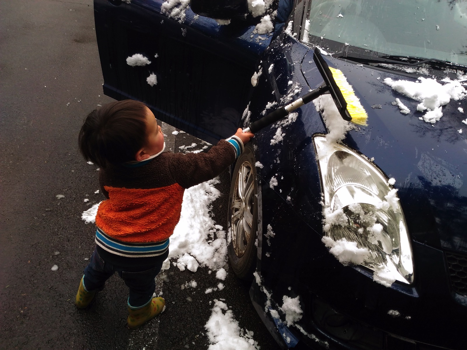 車の雪かきをする子ども
