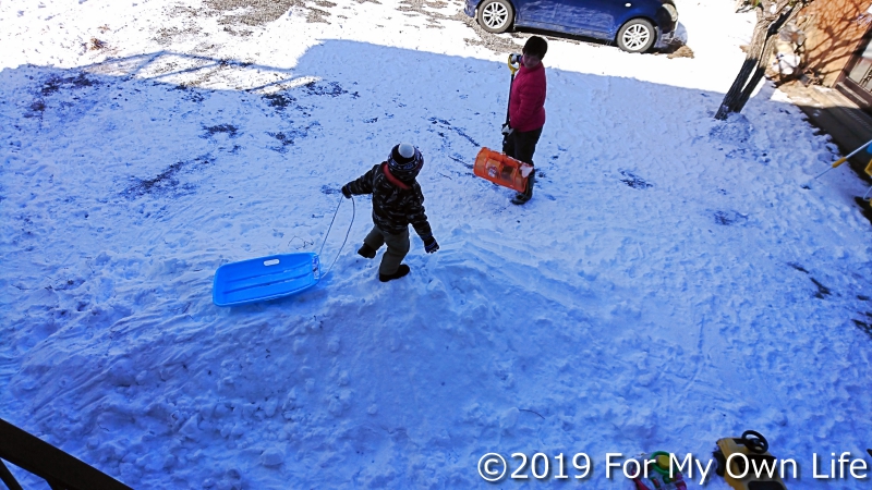 雪で滑り台を作る奥さんと、ソリで滑る息子